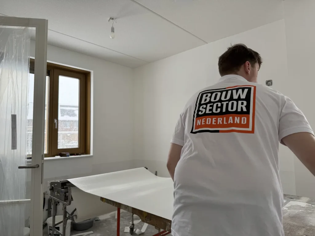 Behanger van Bouwsector Nederland rolt een baan vlies uit over de plaktafel
